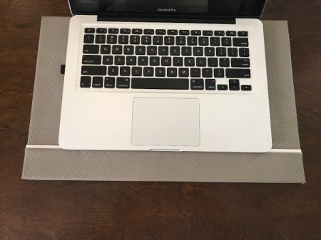 A desk mat under a laptop computer on a wooden desk.