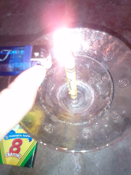 A lit crayon in a candle holder.