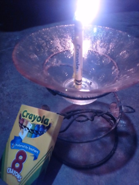 A lit crayon in a candle holder.