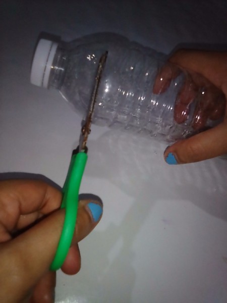 Cutting a plastic bottle with scissors.
