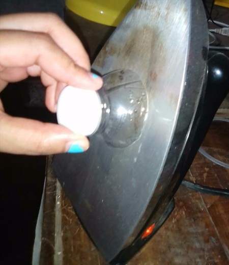 A plastic bottle top being pressed on a hot iron.