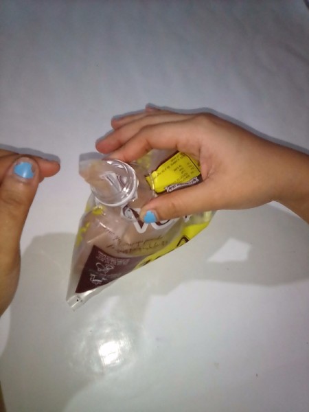 A plastic bottle top with the top of a bag inserted through.