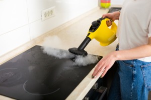 Woman Cleaning stove with Steam Cleaner