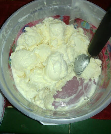 Making scoops in a plastic tub of ice cream.