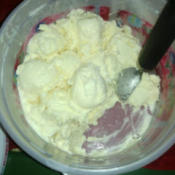 Making scoops in a plastic tub of ice cream.