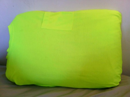 A bright yellow green T-shirt covering a pillow.