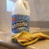 A bottle of ammonia and a cleaning rag in the bathroom.
