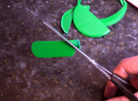 A green plastic lid cut in the shape of a key fob.
