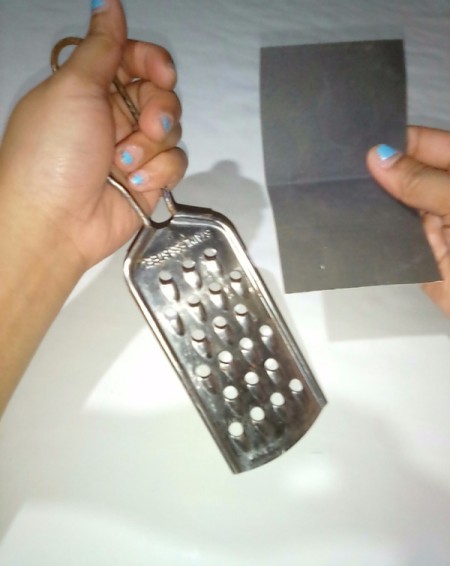 A metal food grater and a piece of fine sandpaper.