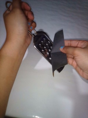 Rubbing sandpaper across a metal food grater.