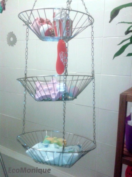 Shower supplies stored in a hanging wire fruit basket.