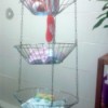 Shower supplies stored in a hanging wire fruit basket.
