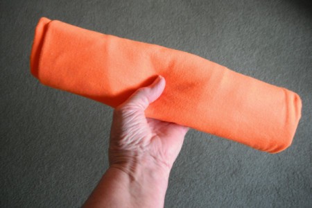 A folded and rolled up orange T-shirt.