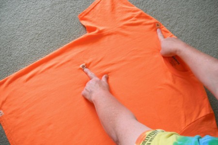 Folding an orange T-shirt.