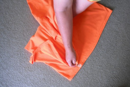 Folding an orange T-shirt.