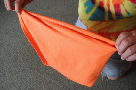 Folding an orange T-shirt.
