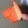 Folding an orange T-shirt.