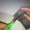 Scissors cutting through sandpaper to sharpen them.