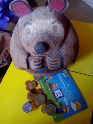 A coin bank with some coins around the base.