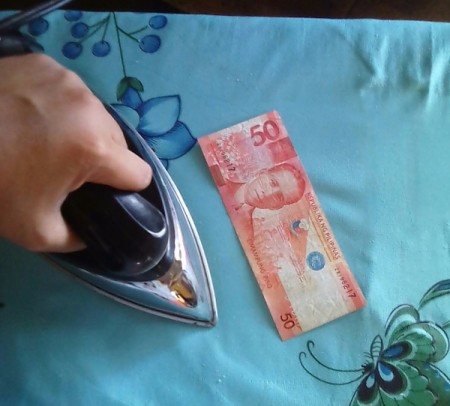 A wrinkled bill from the Philippines, being ironed flat.