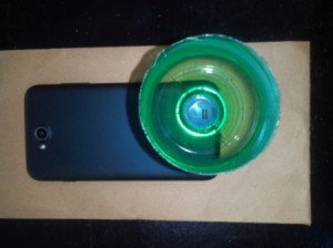 A plastic bottle top placed over the speaker on a phone.