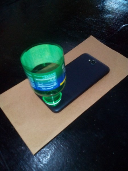 A plastic bottle top placed over the speaker on a phone.