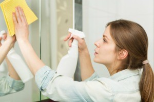 Woman Cleaning Bathroom Mirror