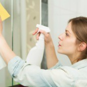 Woman Cleaning Bathroom Mirror