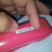 Printed name labels being adhered with tape on a stapler.