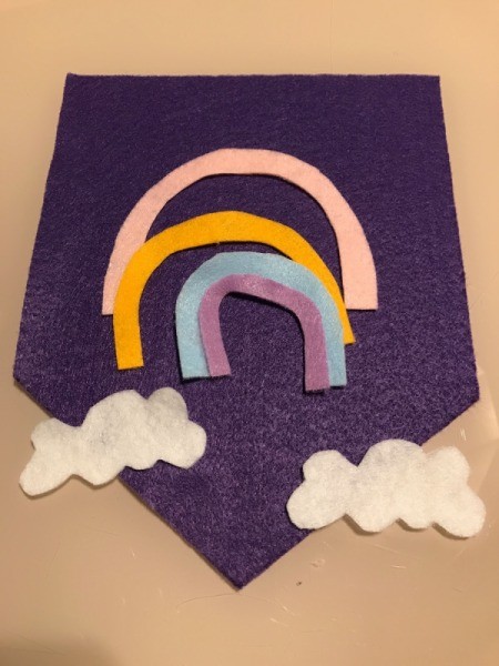 Pennant Flag Wall Decor - pink, yellow, blue, and lavender rainbow stripes on felt along with two clouds cut from white felt