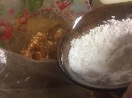 adding flour mixture to marinated chicken