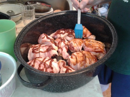 BBQ sauce being brushed on top of bacon wrapped chicken
