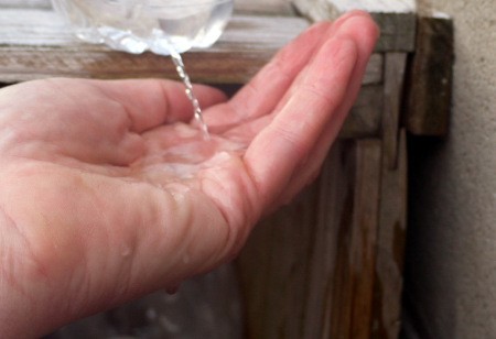 DIY Outdoor Plastic Bottle Handwashing Station - hand under a stream of water
