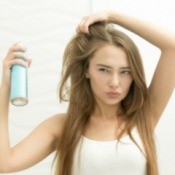 A girl spraying hairspray.