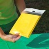 A person holding a yellow plastic tablecloth in their hands.