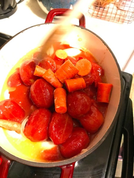 Adding carrots to a batch of tomato soup.