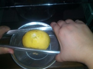 Using a pair of tongs to squeeze juice from a lemon.