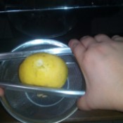 Using a pair of tongs to squeeze juice from a lemon.