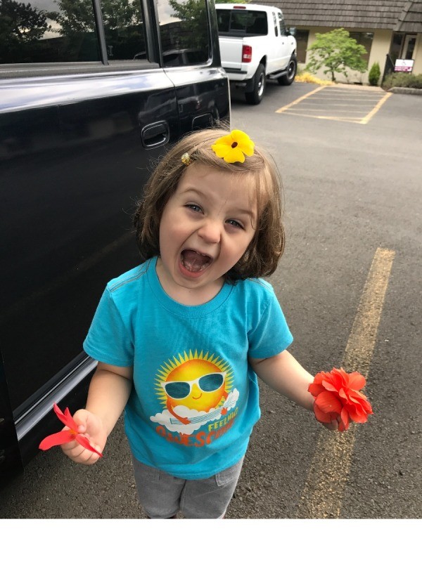 Toddler Fun With Flowers - child holding flowers with one yellow one on the top of his head