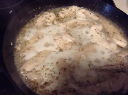 Adding browned chicken into the champagne mixture in the frying pan.