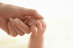 A parent holding their baby's hand.