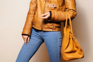 A woman wearing jeans carrying a leather purse.