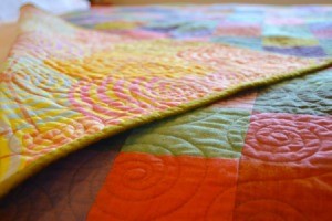 A colorful handmade quilt on a bed.