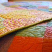 A colorful handmade quilt on a bed.