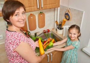 A mom and daughter with vegetables.