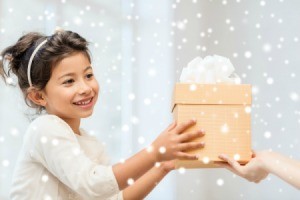 A girl being handed a gift on Christmas.