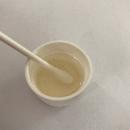 Dipping a Q-tip into a bottlecap of acetone.