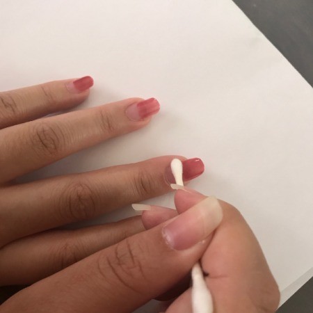 Cleaning excess nail polish from nails.