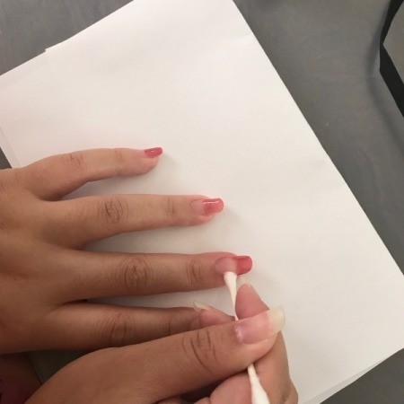 Cleaning excess nail polish from nails.