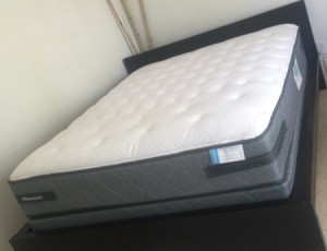 A brand new mattress on a bedframe.